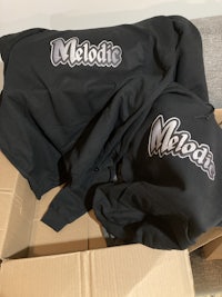 a black hoodie with a logo on it sits on top of a box